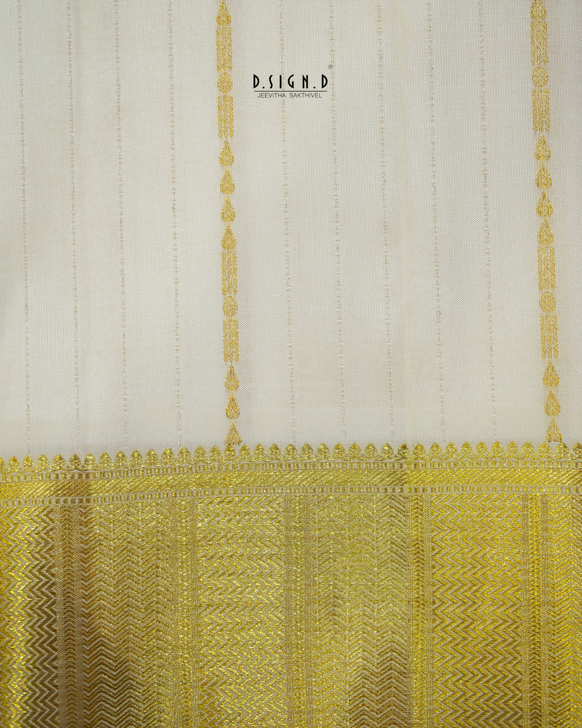 A close-up of a fabric or textile sample with a warm off-white upper section featuring subtle vertical stripes and a wide ornate gold patterned border along the bottom.