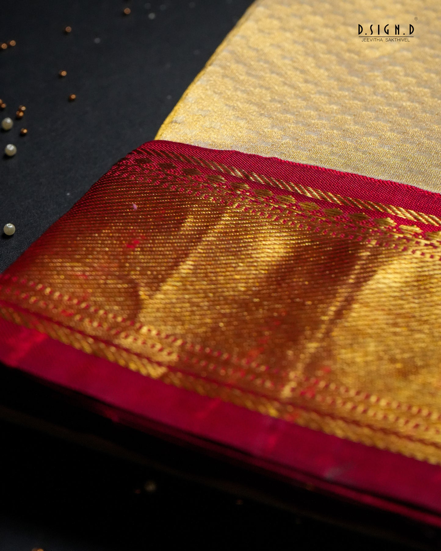 A close-up of a traditional Indian silk shirt fabric, showcasing a rich gold body with a deep red border and intricate metallic gold zari weaving, set against a dark background .