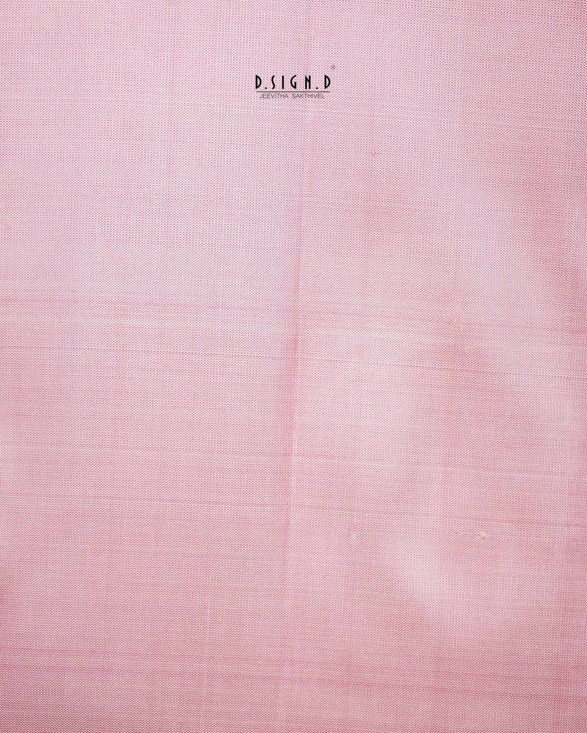 A close-up of a light pink fabric with a subtle woven texture.