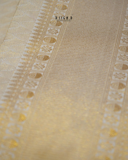 A close-up of a light beige fabric with intricate gold woven patterns and borders.