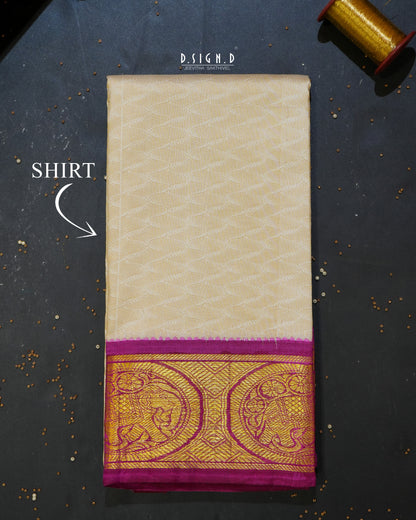 A folded cream-colored silk shirt material or fabric piece with a wide magenta and gold zari border, displayed on a dark textured surface with a spool of gold thread in the corner.