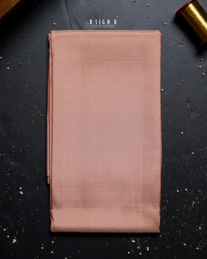 A folded copper shade fabric , likely a shirt material , is displayed flat on a dark textured background with decorative gold props in the corners.