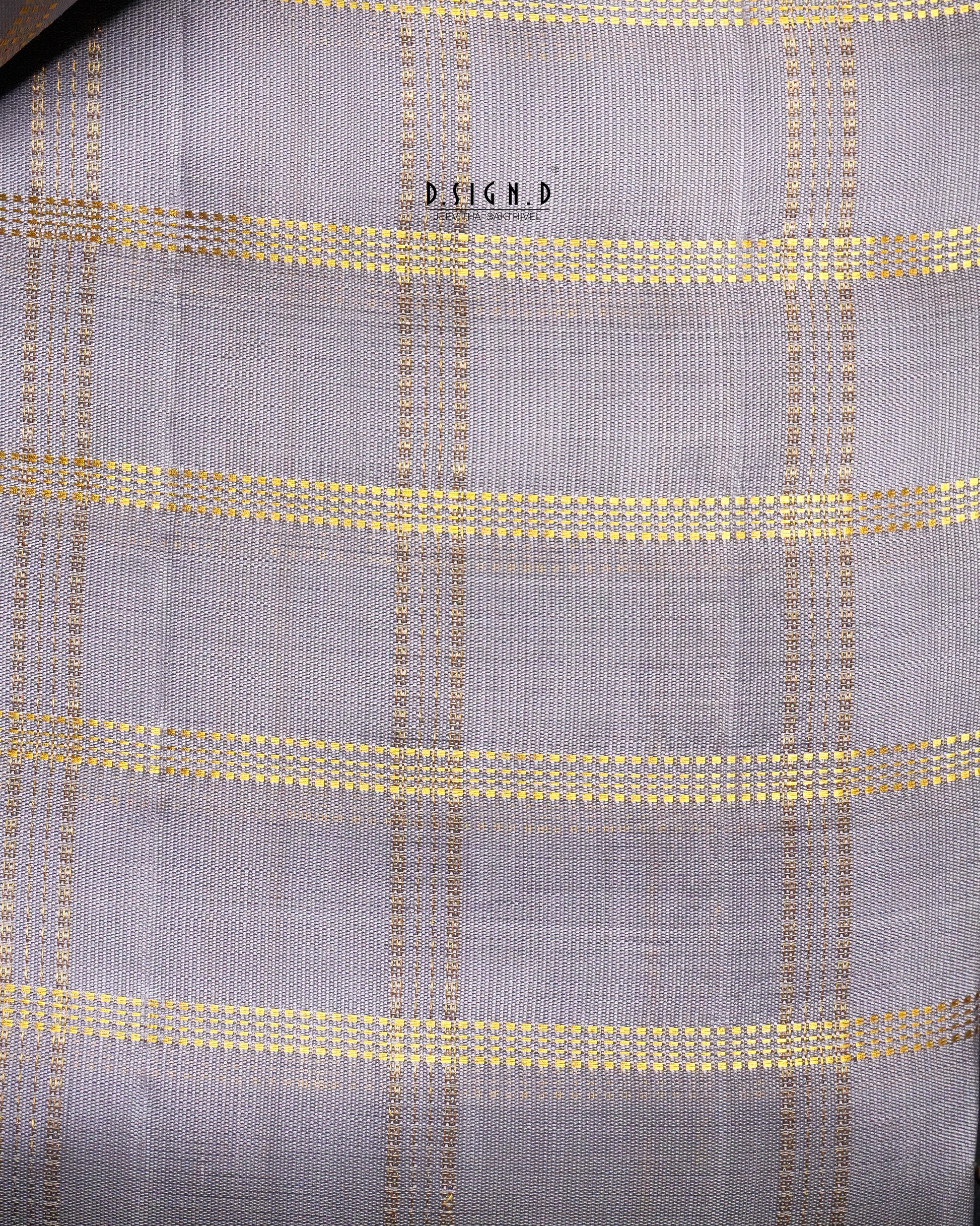 A close-up of a woven fabric with a mauve base and a gold checkered plaid pattern. 
