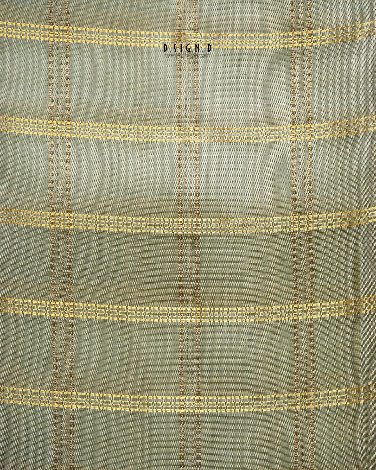 A close-up of a woven fabric with a muted pista green base and horizontal stripes of gold and brown woven dots.