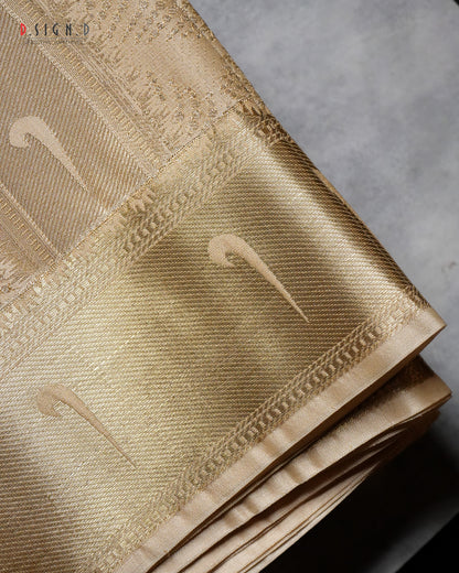 A close-up of a folded gold silk fabric with a textured weave and subtle woven motifs, set against a neutral gray background.