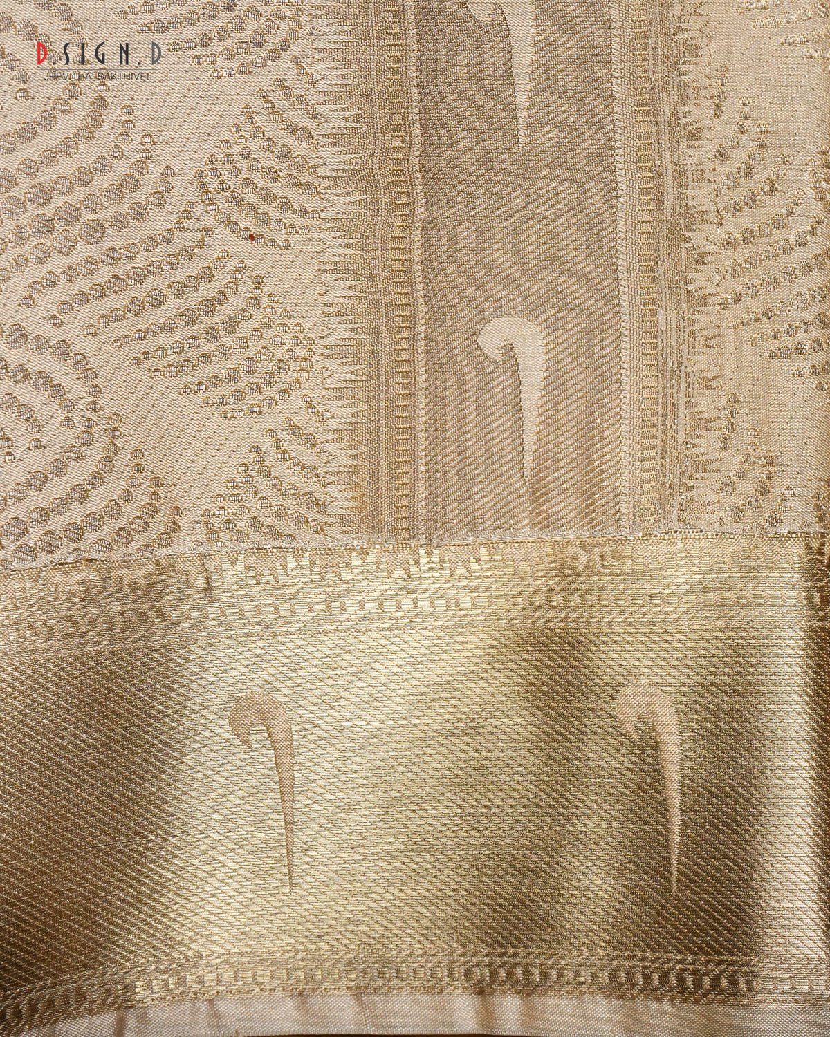 A close-up of a gold woven fabric with intricate metallic patterns and a wide decorative border.