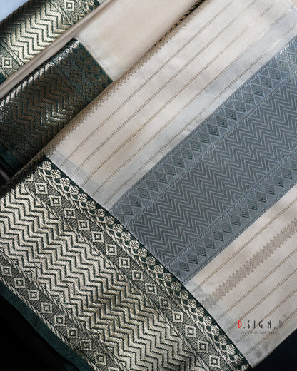 A close-up of a woven textile with striped panels in cream, green, plus ornate metallic borders in gold and dark green with geometric patterns.