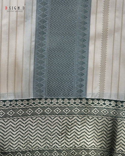 A close-up of a woven textile with vertical panels in cream, green, featuring geometric and chevron patterns with a decorative border.