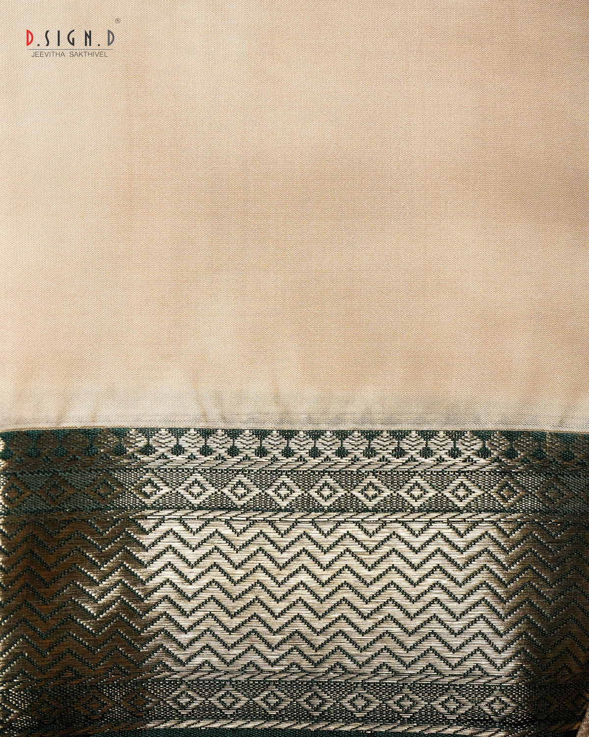 A close-up of a beige fabric (shirt bit) with a wide decorative woven border at the bottom, featuring green & gold metallic chevron and diamond patterns. 