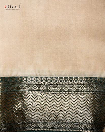 A close-up of a beige fabric (shirt bit) with a wide decorative woven border at the bottom, featuring green & gold metallic chevron and diamond patterns. 