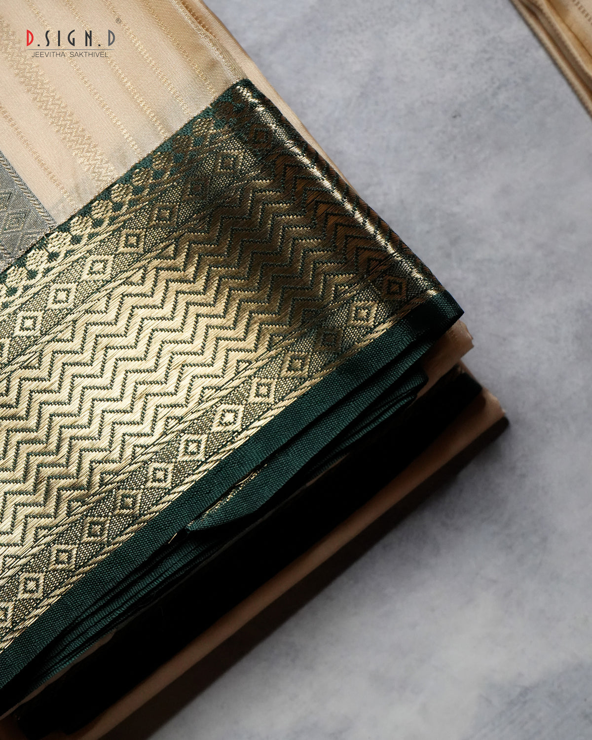 A folded dark green and gold brocade fabric with intricate woven geometric patterns, displayed on a neutral gray surface.