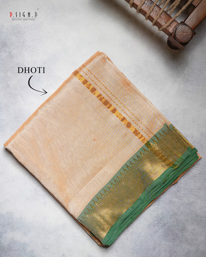 A folded beige pure silk dhoti with a green and gold border, displayed on a textured gray surface with a wooden loom prop in the top right corner.