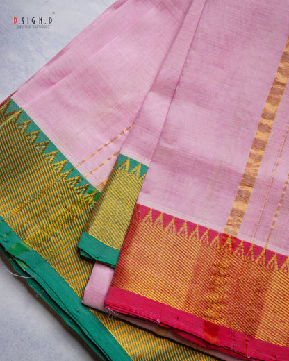 A folded pink silk dhoti & vastram with a wide golden-yellow zari border, featuring green and pink geometric accents, displayed on a light gray surface.