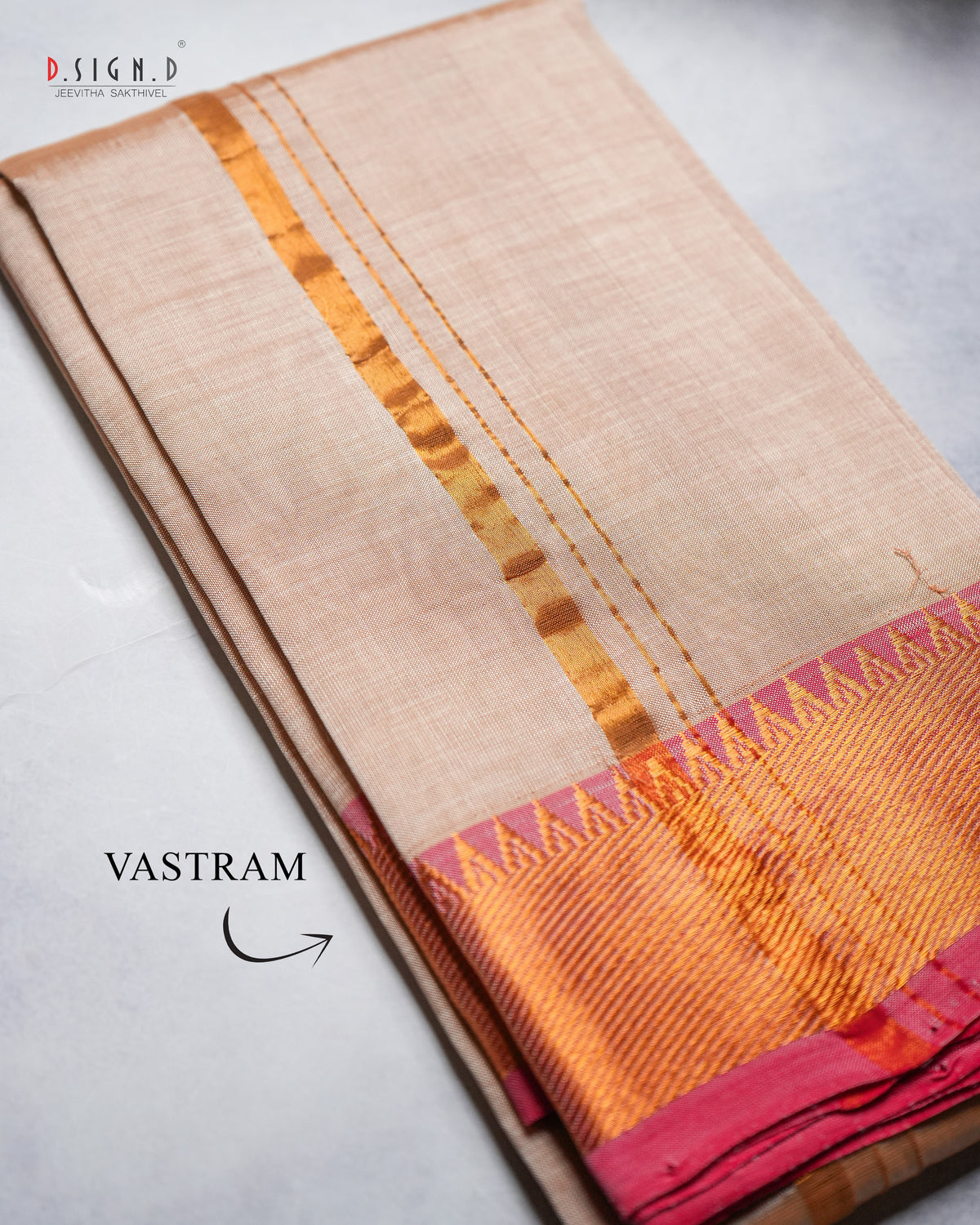 A folded copper silk vastram with a metallic gold Vastram pattern and a red and gold border.