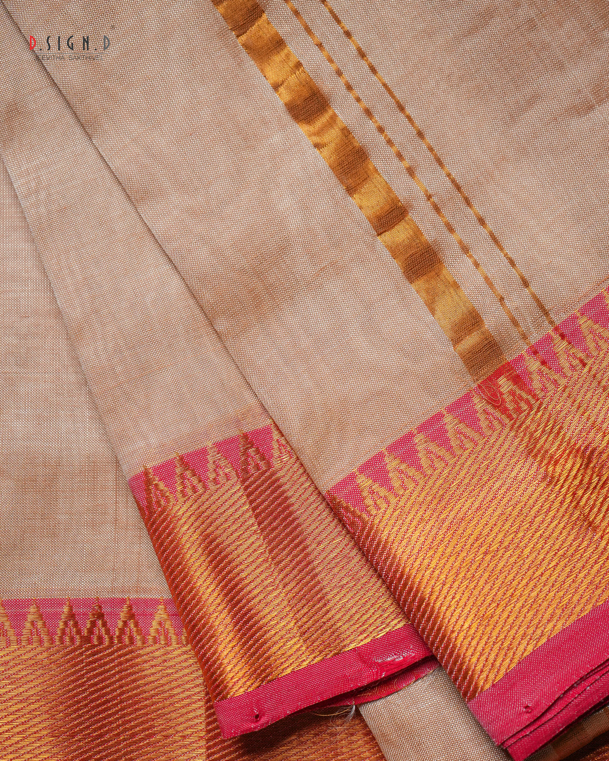 A close-up of a copper silk dhoti with a vibrant red zari border, showing the texture and weave details.
