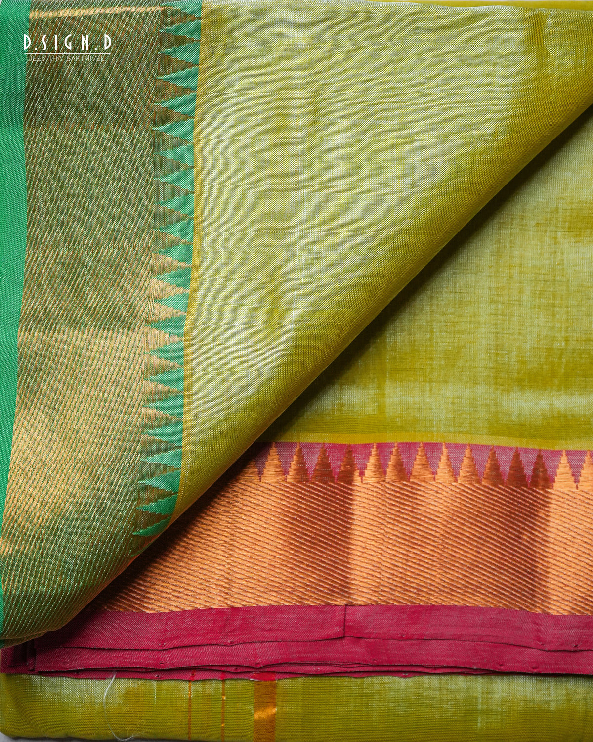 A folded and draped silk dhoti & vastram with a light olive green body, a green and gold patterned border, and a wide orange and magenta zari border.