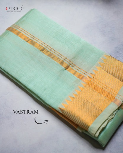A folded mint green vastram with a wide golden border, displayed on a textured light gray surface. 