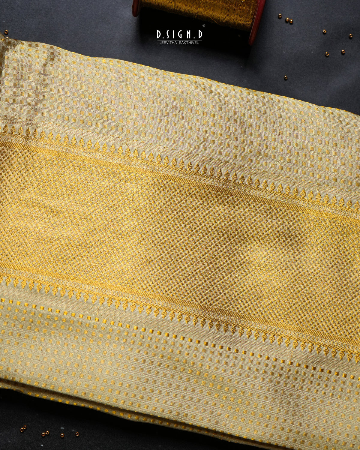 A folded piece of light pista green dhoti set with a fine dotted pattern and decorative woven borders, displayed on a dark textured surface with a small branded tag visible near the top.