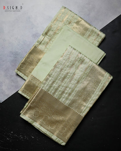 A folded light green and gold brocade fabric, likely a Dhoti or textile, displayed on a split gray and black background. The fabric features intricate metallic gold zari patterns, a detailed border, and a solid light green inner layer.