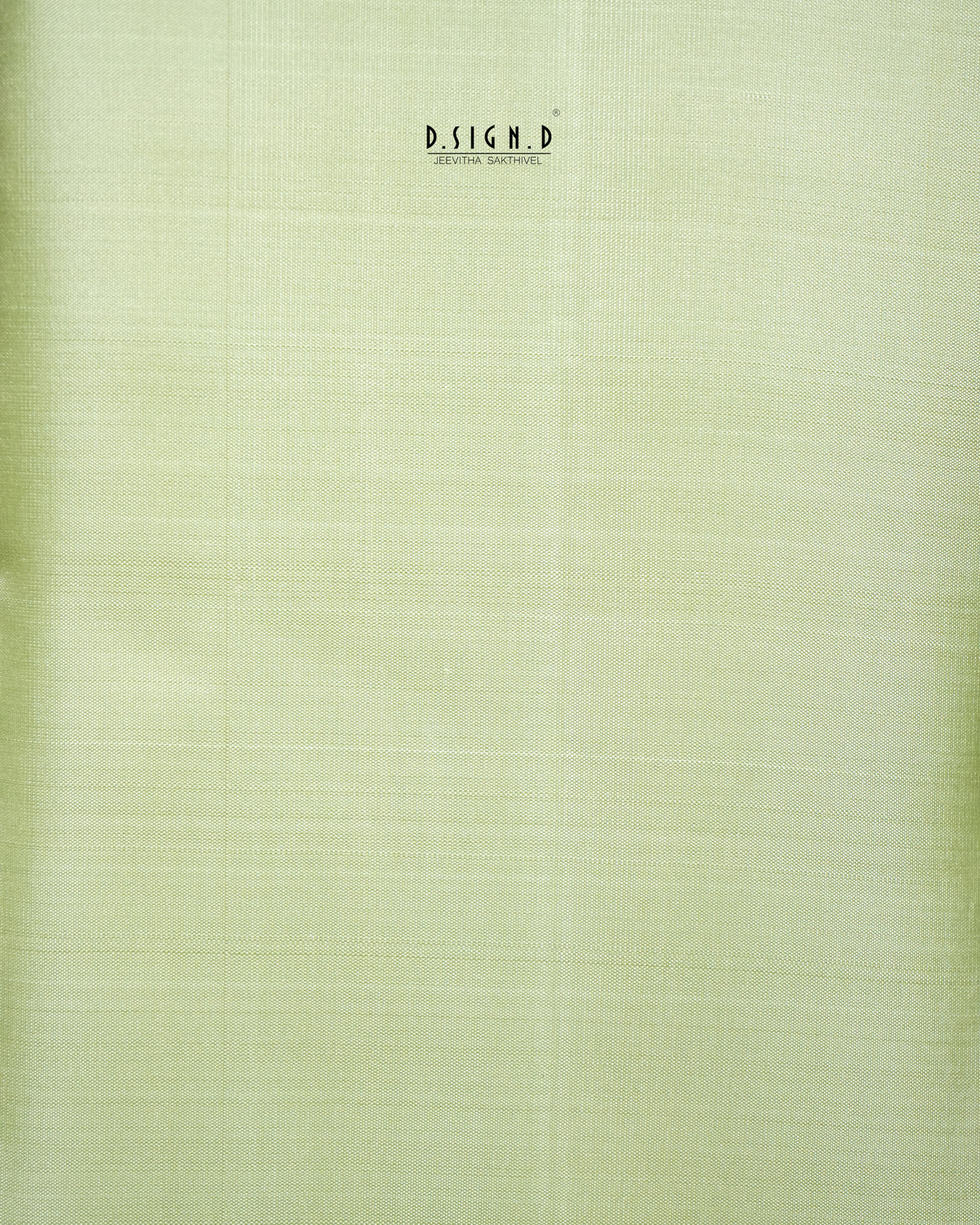 A close-up of a pale yellow-green dhoti or material swatch with a subtle woven texture.