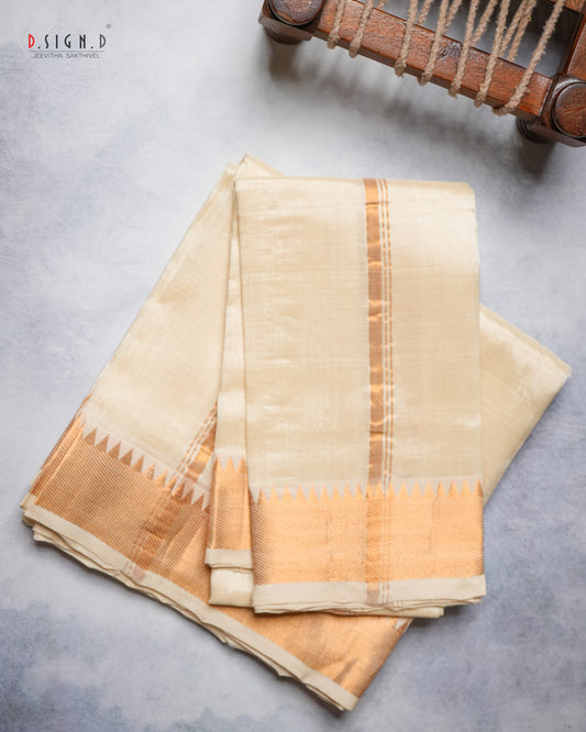 A folded cream-colored silk dhoti with a gold border and vertical stripes, displayed on a textured gray surface next to a wooden loom machine.