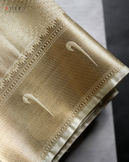 A close-up of a folded gold fabric with a woven pattern, featuring two stylized white swooshes and decorative stitched borders, set against a dark gray background.