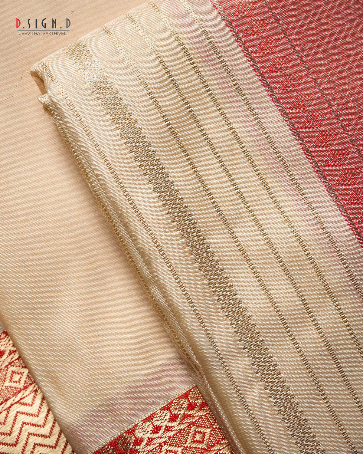A folded beige and red dhoti fabric with metallic gold zari woven stripes and borders, alongside a red patterned section.
